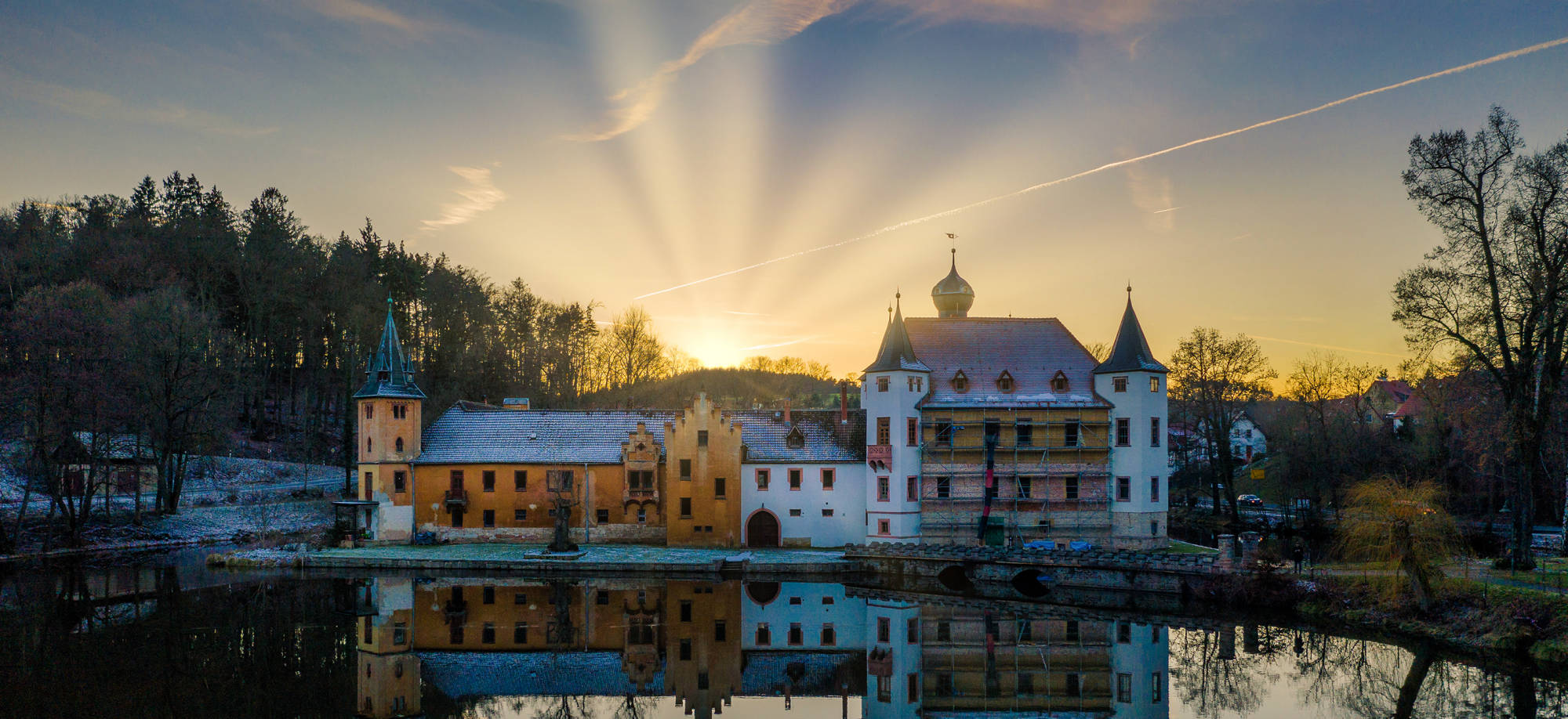 Schloss Wolfersdorf im Abendlicht, gespiegelt im künstlich angestauten Teich
