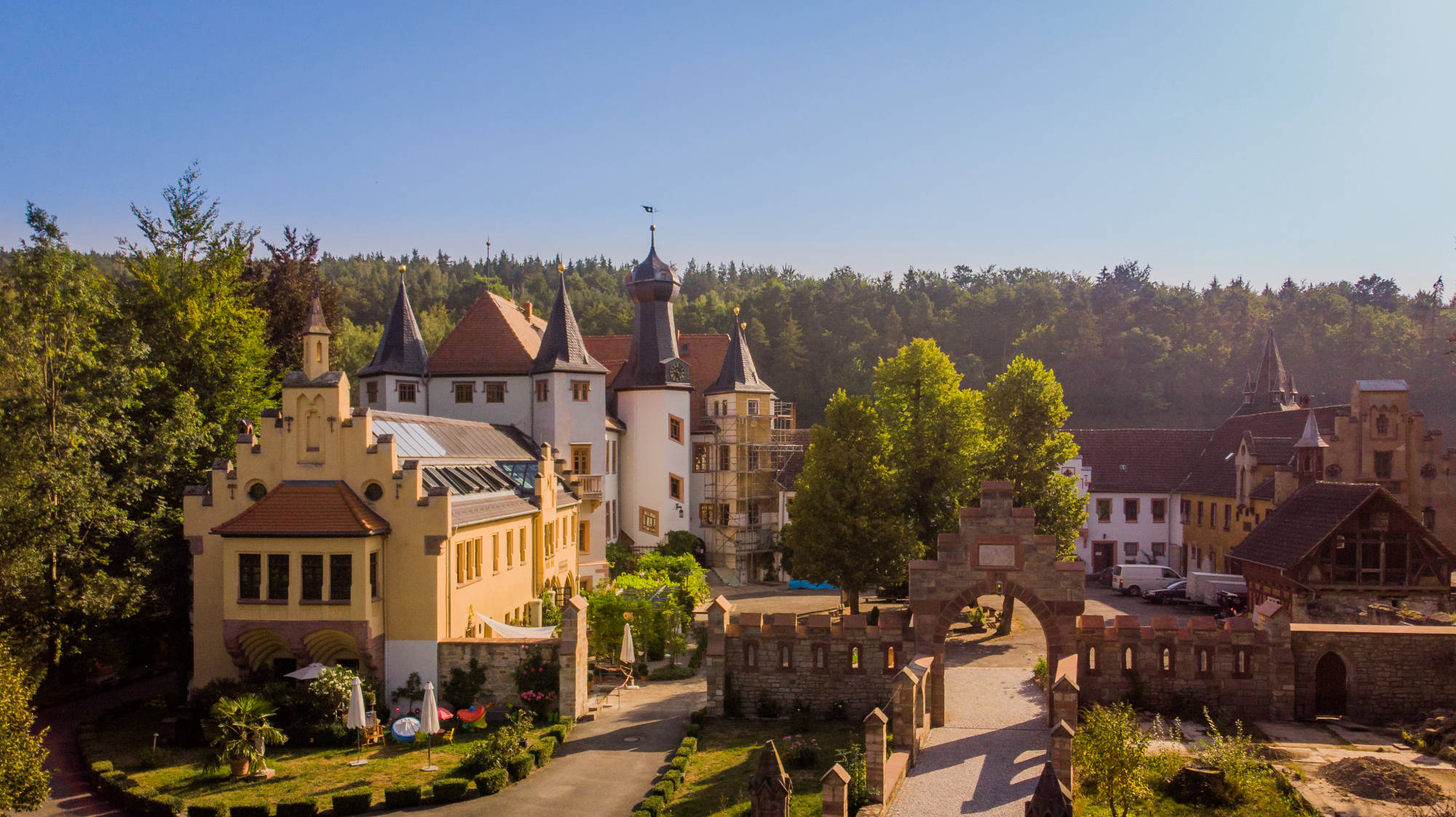 Die Schlossanlage mit Teich aus der Luft im Morgenlicht