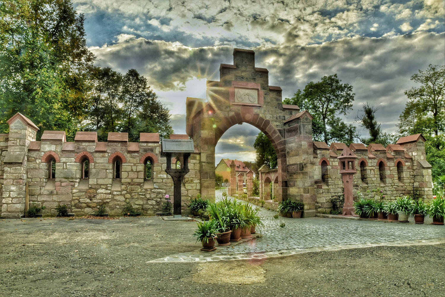 Das Schlosstor der Anlage mit Natursteinmauer und Bepflanzung