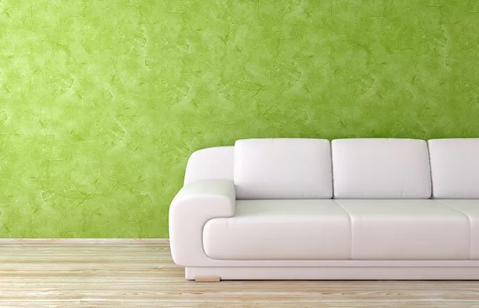 Grün gestaltete Wand mit Spachteltechnik hinter weißem Sofa